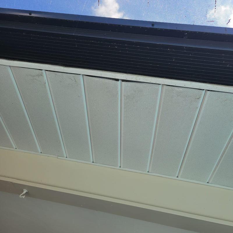 Soffit panels under roof eave with mesh screen ventilation