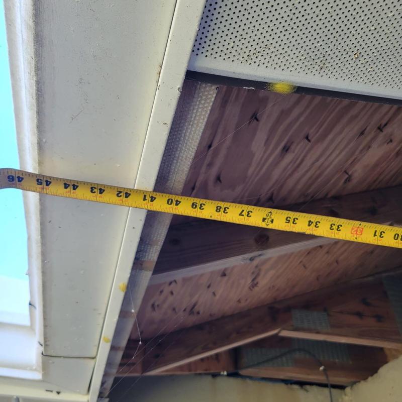 Soffit vent repair with measuring tape in attic space