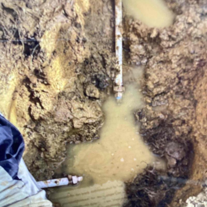 Water line leak in muddy trench excavation site