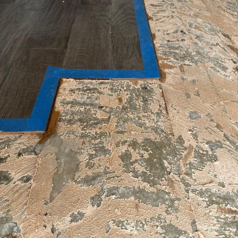 Flooring underlayment removal showing adhesive residue and tape