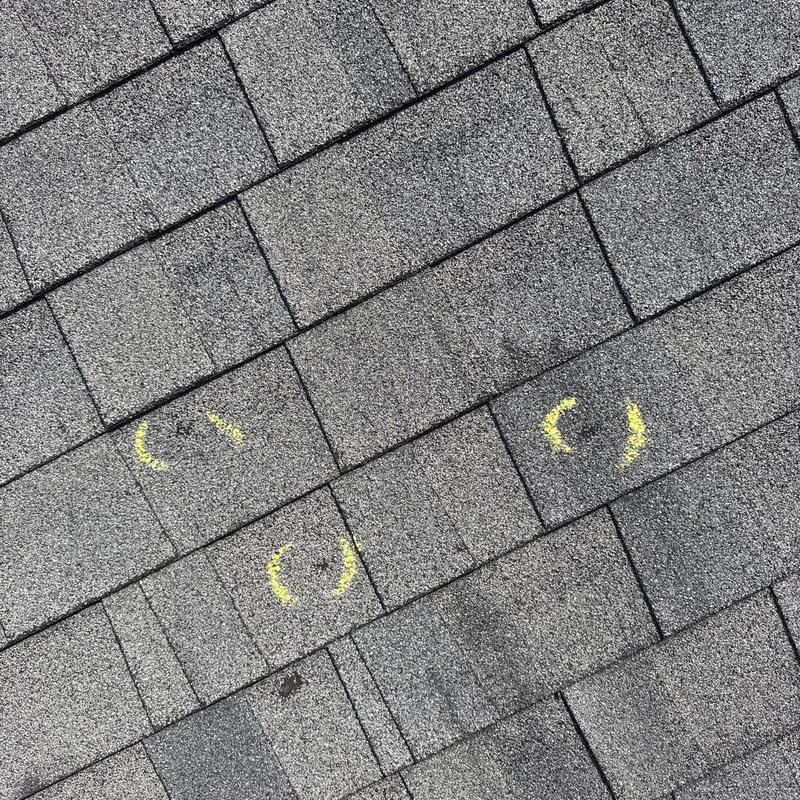 Roof shingles with hail damage marked in yellow