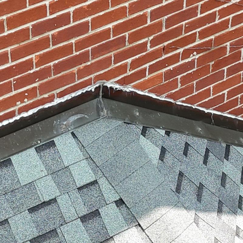 Roof shingles and metal flashing on brick wall corner
