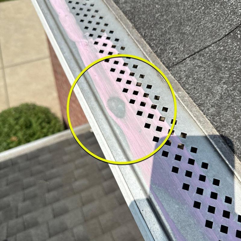 Metal gutter guard with hail damage circled in yellow