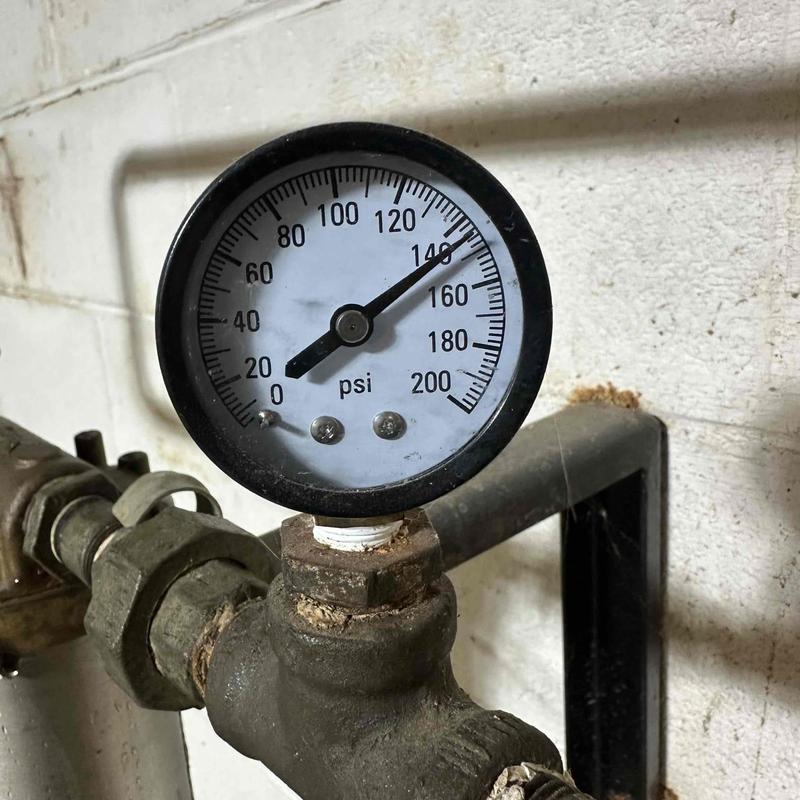 Pressure regulator gauge on water heater piping system