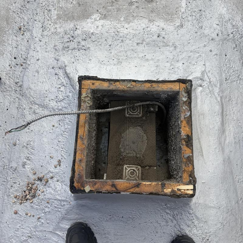 Exhaust fan housing with exposed wiring on roof surface