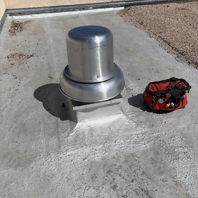 Exhaust fan on flat roof with tool bag nearby