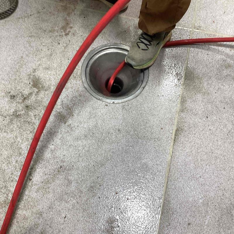 Floor drain with red cable and worker's foot