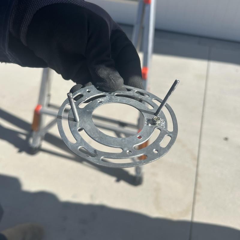 Exterior light fixture mounting bracket held by gloved hand Exterior light fixture mounting bracket held by gloved hand