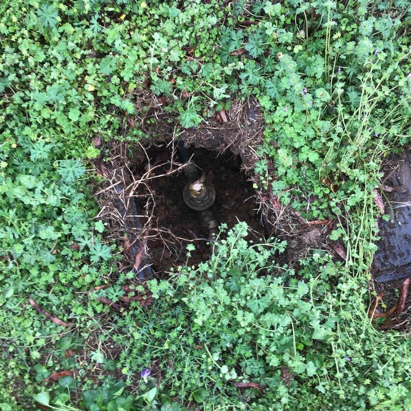 PRV valve exposed in dug ground hole surrounded by grass