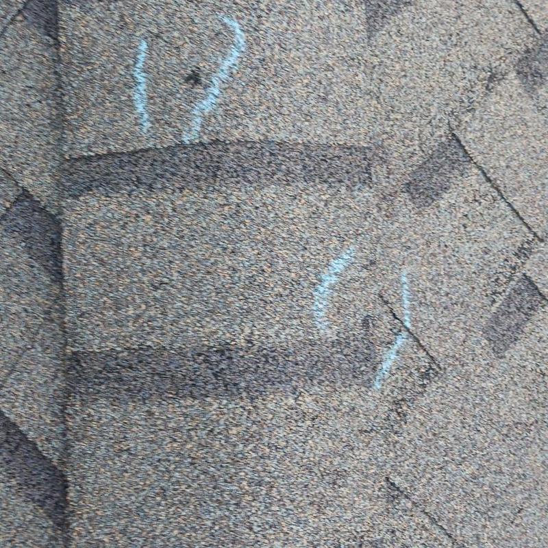 Asphalt roof shingles with storm damage marks