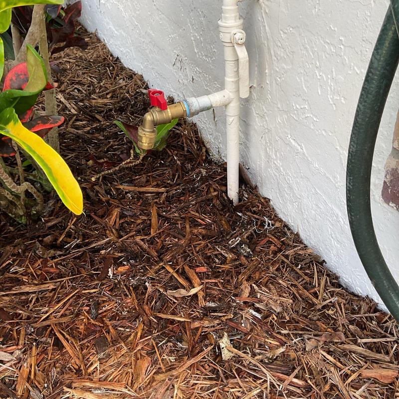 Quarter turn hose bib with red handle on house exterior