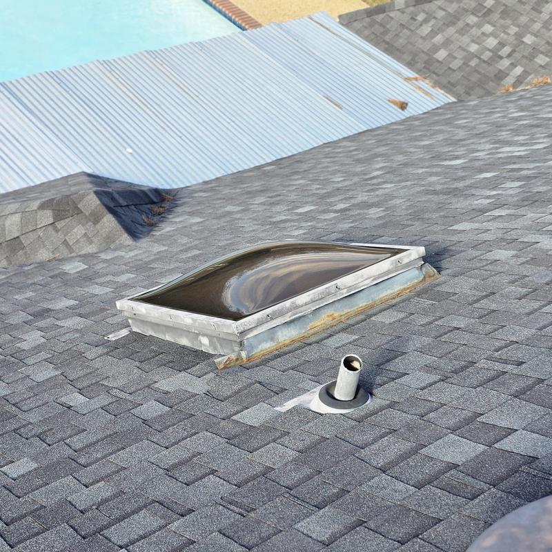 Skylight dome with hail damage on asphalt roof