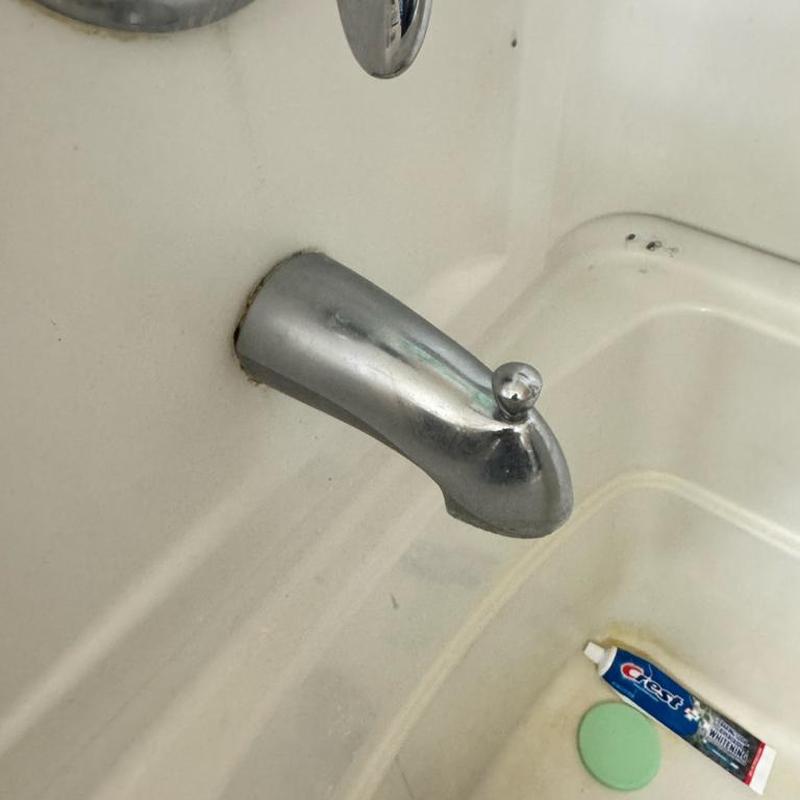 Slip-on style tub spout installed on bathtub wall