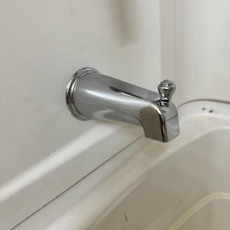 Slip-on tub spout with diverter knob installed on tub wall
