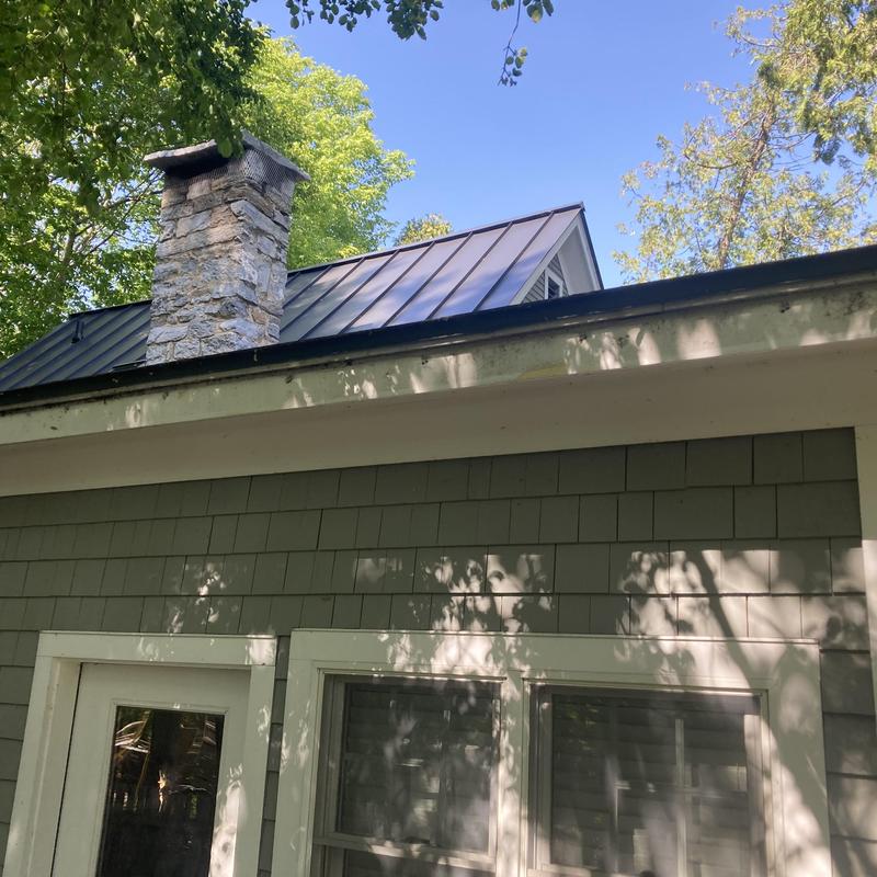 Metal roof panels on residential home with chimney Metal roof panels on residential home with chimney