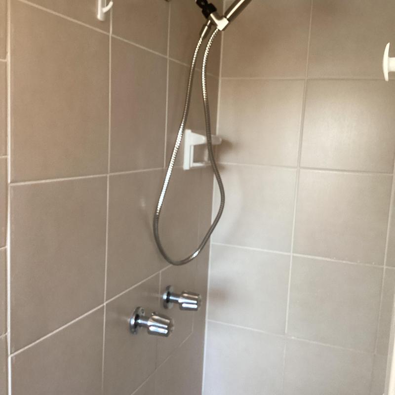 Shower faucet stems and chrome shower head on tiled wall