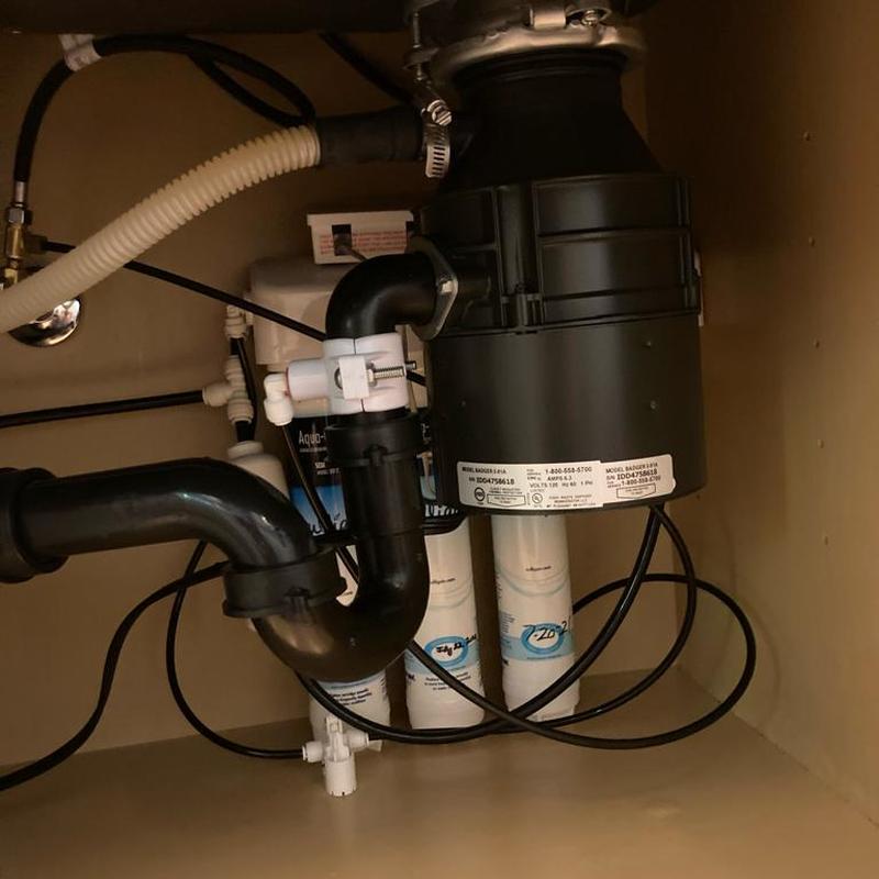 Garbage disposal unit with connected drain pipes under sink