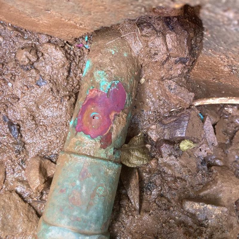 Copper water main with corrosion hole in soil