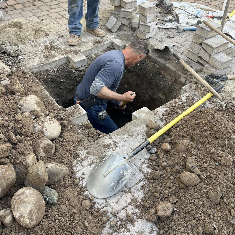 Sewer line excavation with pavers and tools nearby