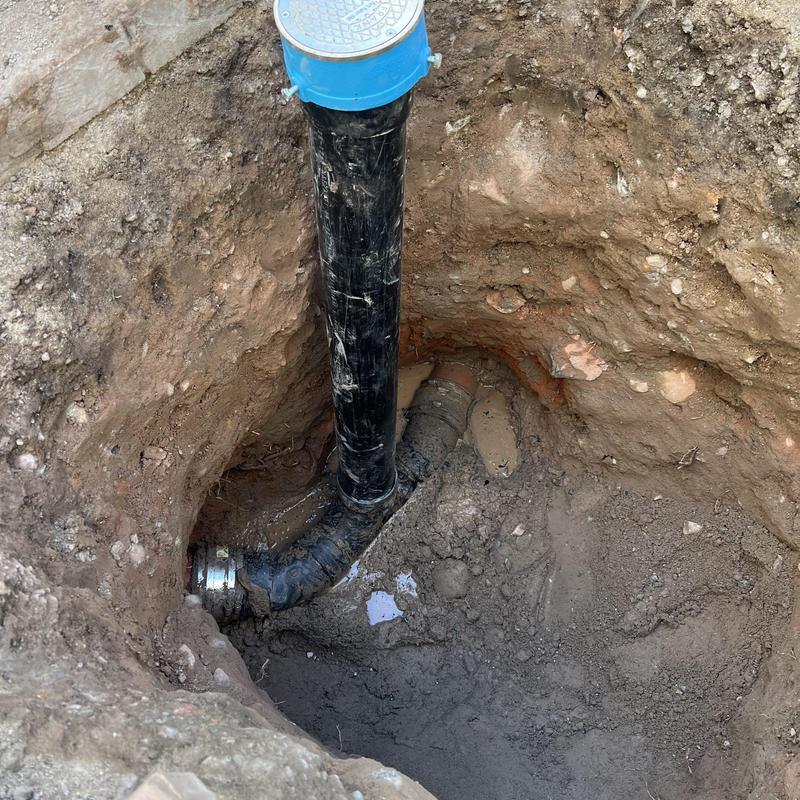 Sewer cleanout pipe installation in excavated soil pit