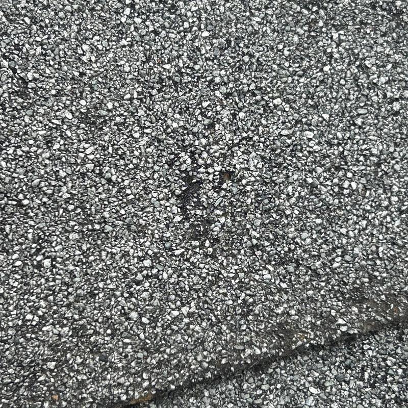 Asphalt shingle roofing close-up showing minor damage
