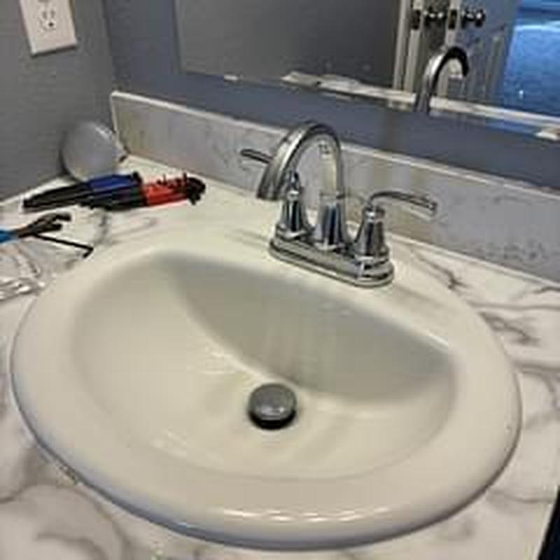 Bathroom sink faucet with chrome handles and tools nearby