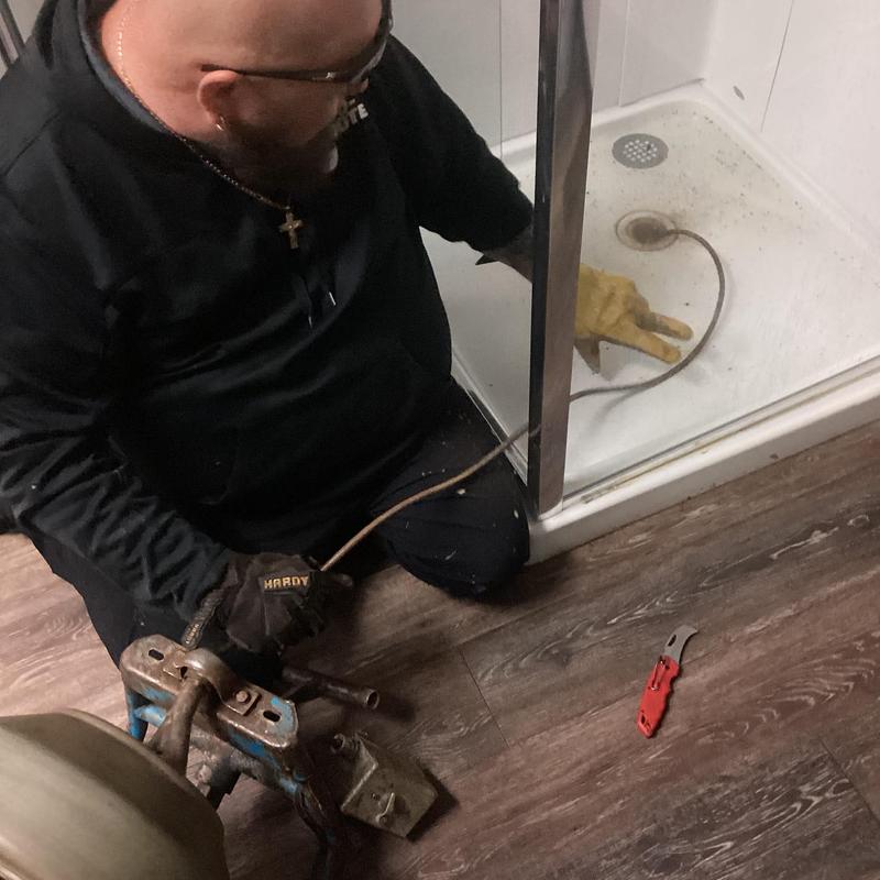 Shower drain clog removal with plumber tools in shower