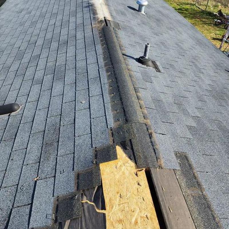 Asphalt shingle roof with exposed wood sheathing and ridge vent removal