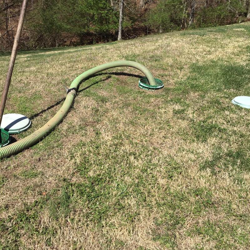 Septic tank pumping hose inserted in tank lid