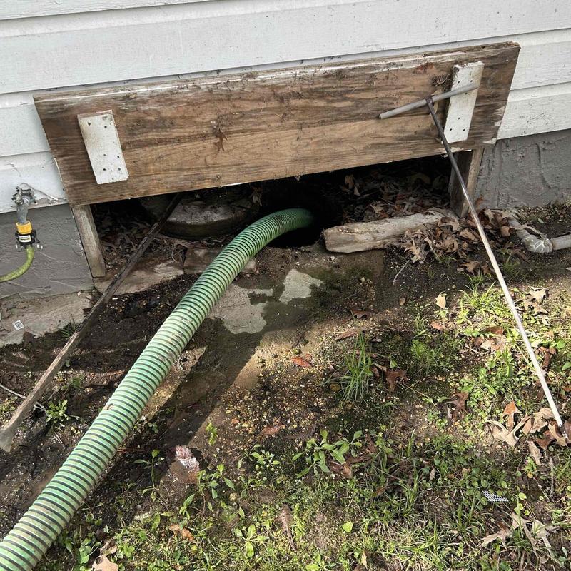 Septic tank access with green suction hose outdoors