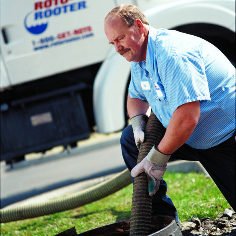 Septic tank pumping hose handling by technician outdoors