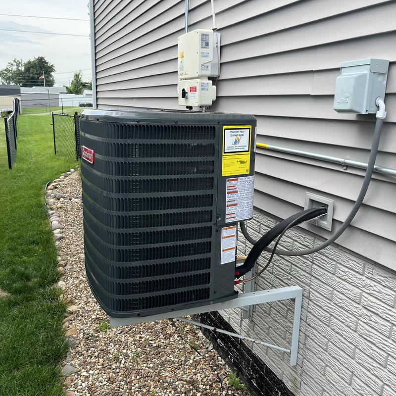 Goodman air conditioner unit mounted on wall outdoors