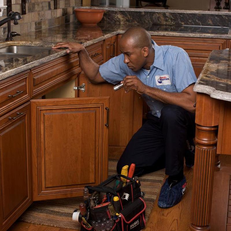 Kitchen sink plumbing inspection with flashlight in cabinet