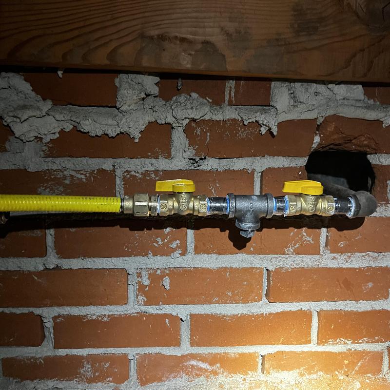 Gas line with yellow shutoff valves on brick wall