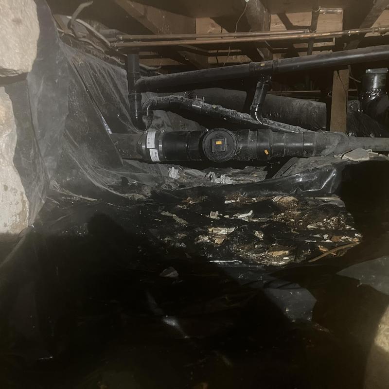 Sewer cleanout in basement crawlspace with debris