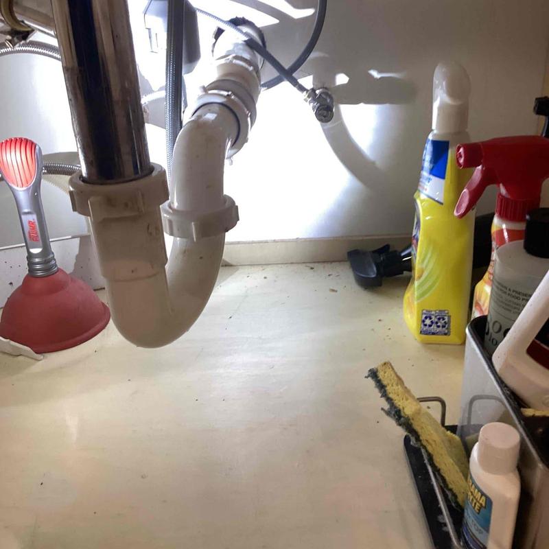 Sink drain pipe with cleaning tools and products under cabinet