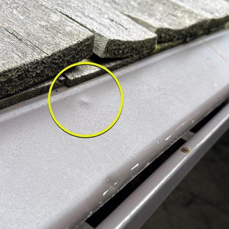 Metal roof drip edge with dent and shingle wear