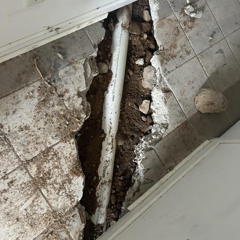 Sewer pipe exposed beneath broken tile floor in repair site Sewer pipe exposed beneath broken tile floor in repair site