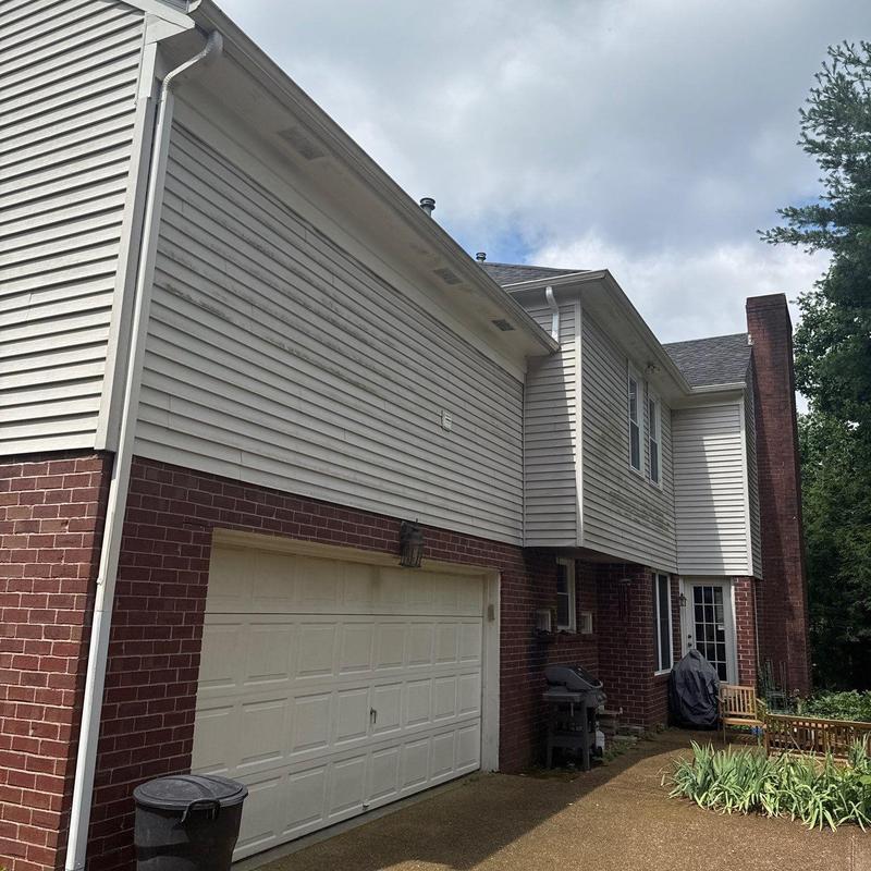Garage door exterior with white siding and brick facade