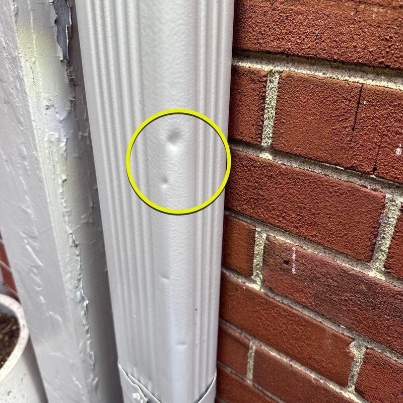 Vinyl downspout with hail damage dents and dings