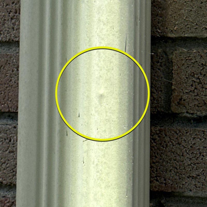 Metal downspout dent with impact damage and scratches