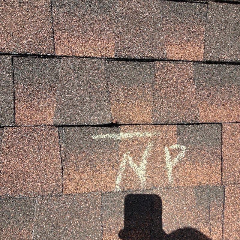 Asphalt roof shingles with hail damage marked for repair
