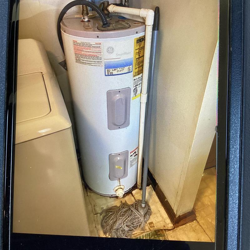 Water heater leaking at base with mop nearby