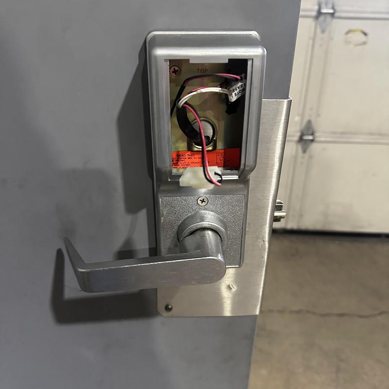 Keypad lock with exposed wiring on metal door