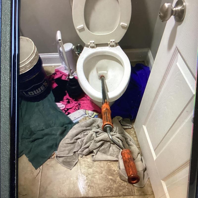 Toilet auger clearing blockage in upstairs commode restroom