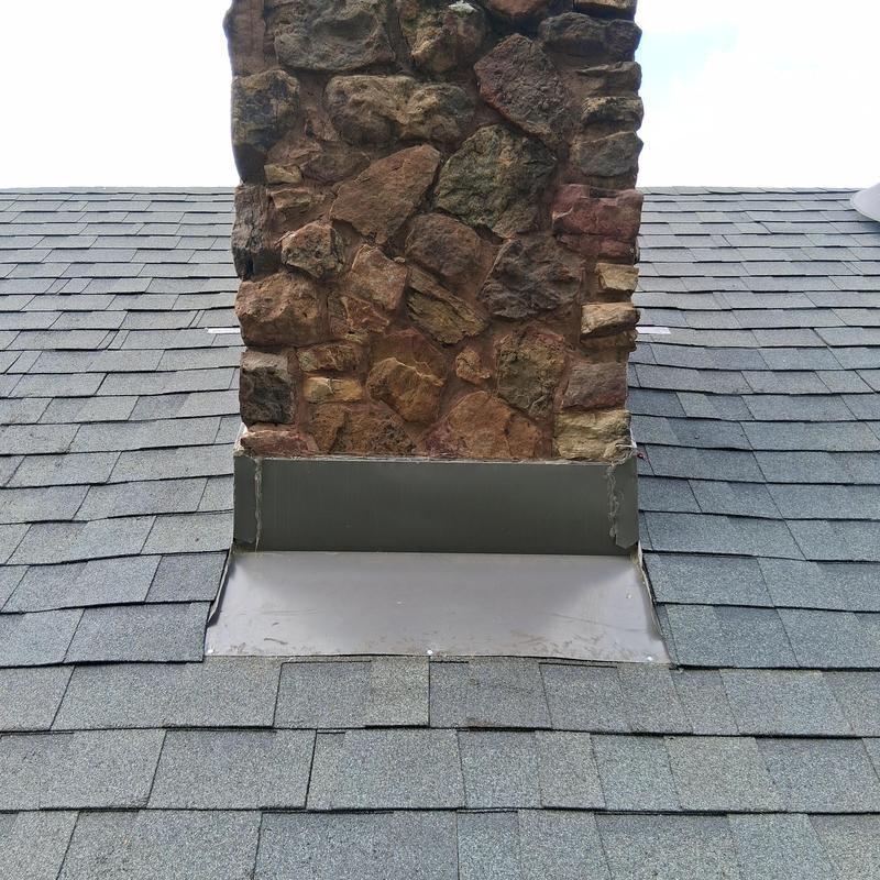Chimney flashing with new shingles on asphalt roof