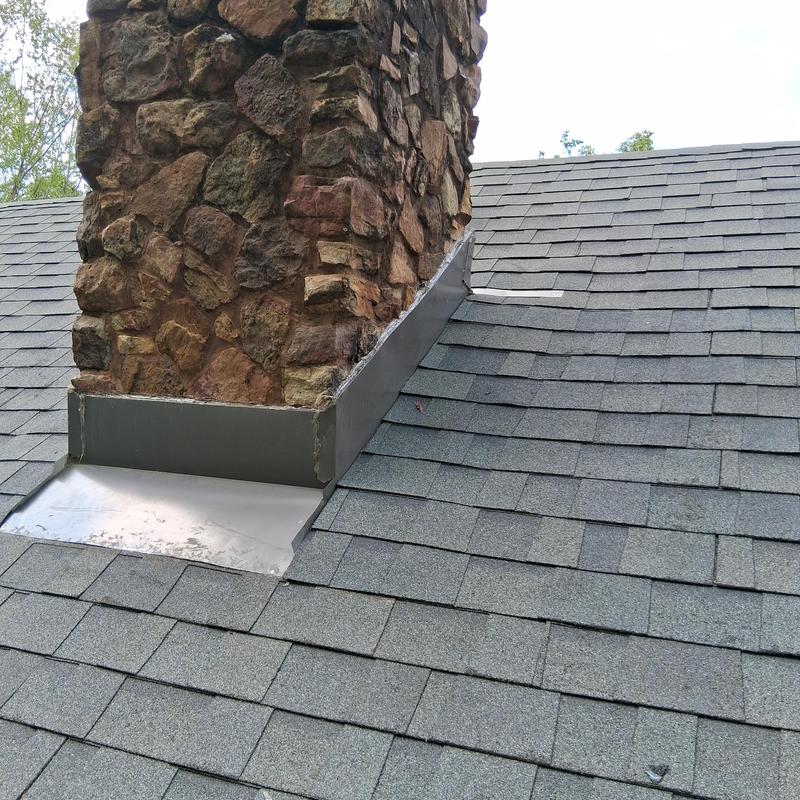 Chimney flashing with new asphalt shingles on roof