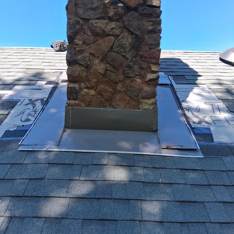 Chimney flashing on shingled roof in daylight