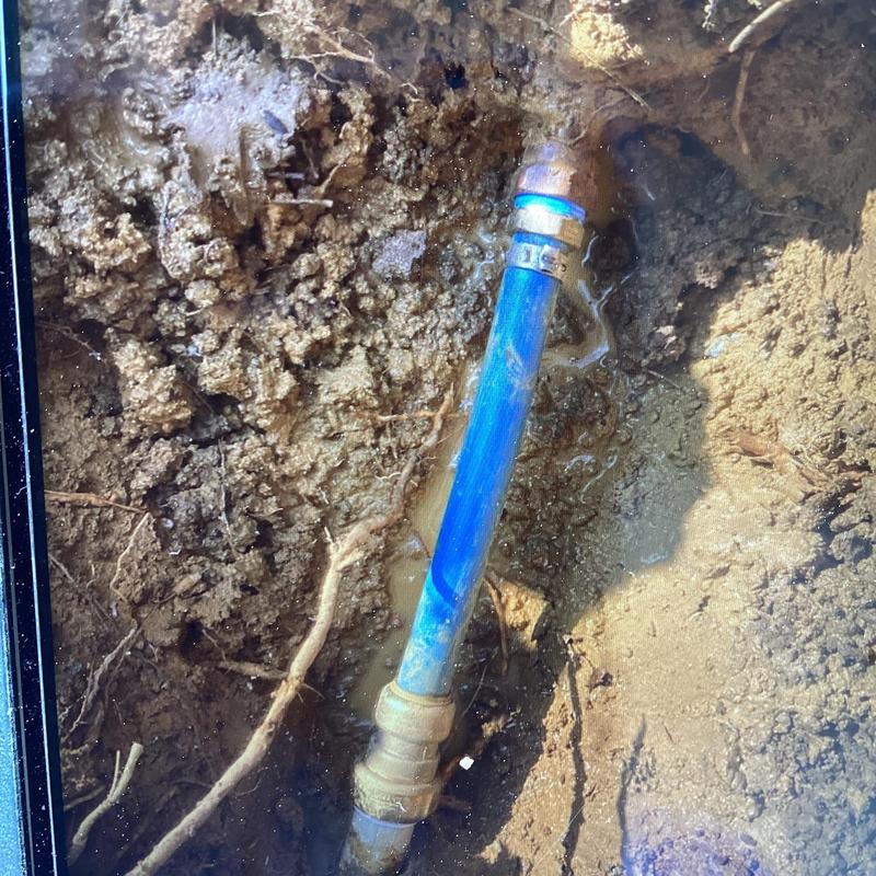 Blue PVC water line with metal fittings underground repair