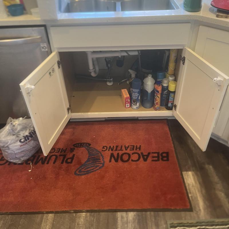Kitchen sink drain line open under cabinet with cleaning supplies Kitchen sink drain line open under cabinet with cleaning supplies